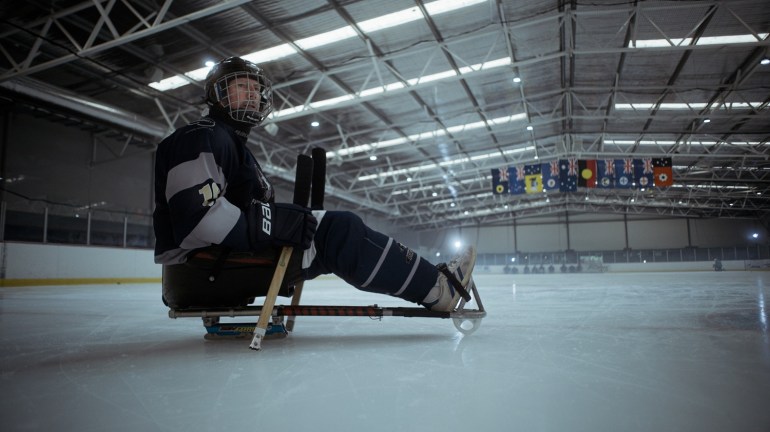 A para-ice hockey player in full gear shown on an ice rink